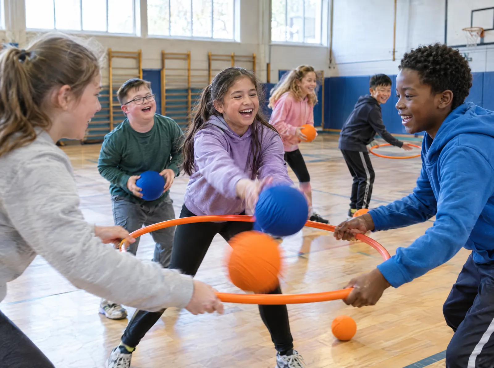 Des enfants rient en jouant avec des ballons et des cerceaux au gymnase